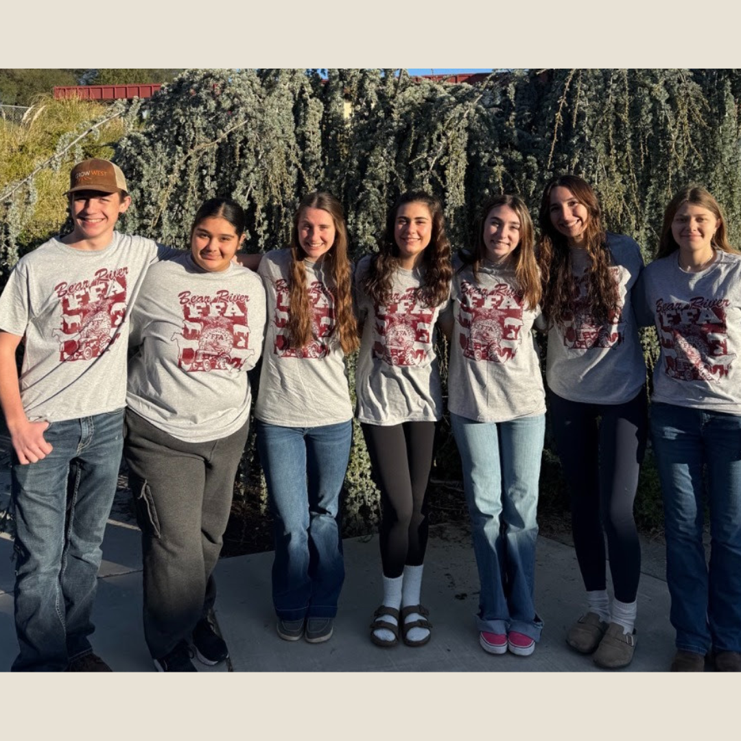 Group of people wearing matching shirts with a logo and text, standing outdoors.