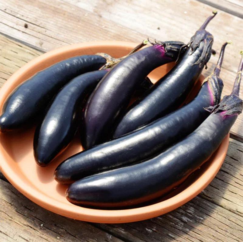 A clay plate full of Millionaire Eggplant against a wooden plank background 