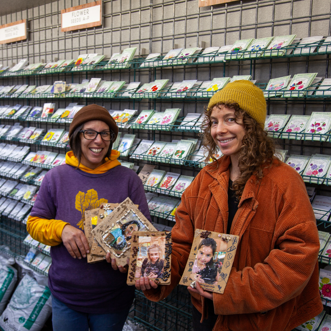 Two women holding photo albums in a store with shelves in the background