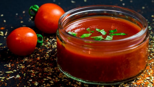 Glass bowl of fresh tomato sauce with basil and whole tomatoes