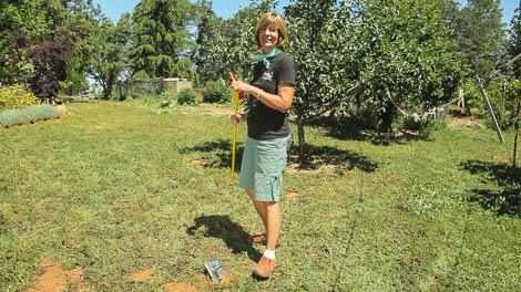 Gardener demonstrating a gopher-control applicator in an orchard
