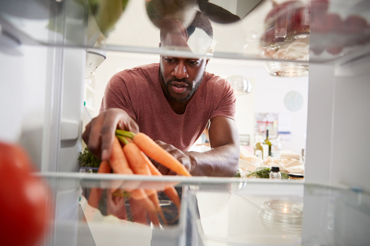 Man putting carrots in refrigerator