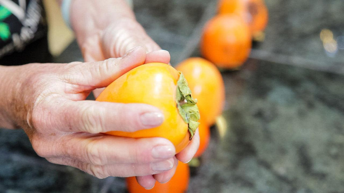 Hands cutting a ripe orange persimmon