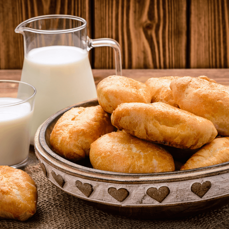 Russian potato piroshki beside a pitcher of milk