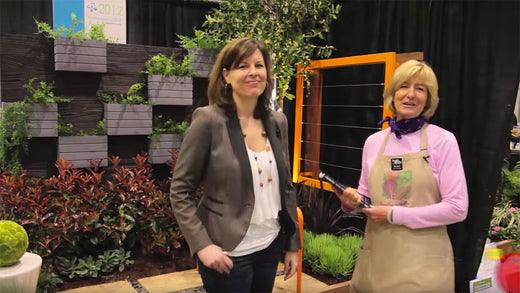Two women standing beside edible garden plants