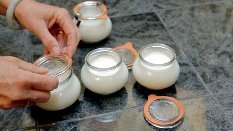 Hands preparing homemade yogurt in small glass jars