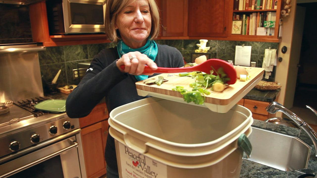 Woman adding kitchen scraps to a large bokashi bucket