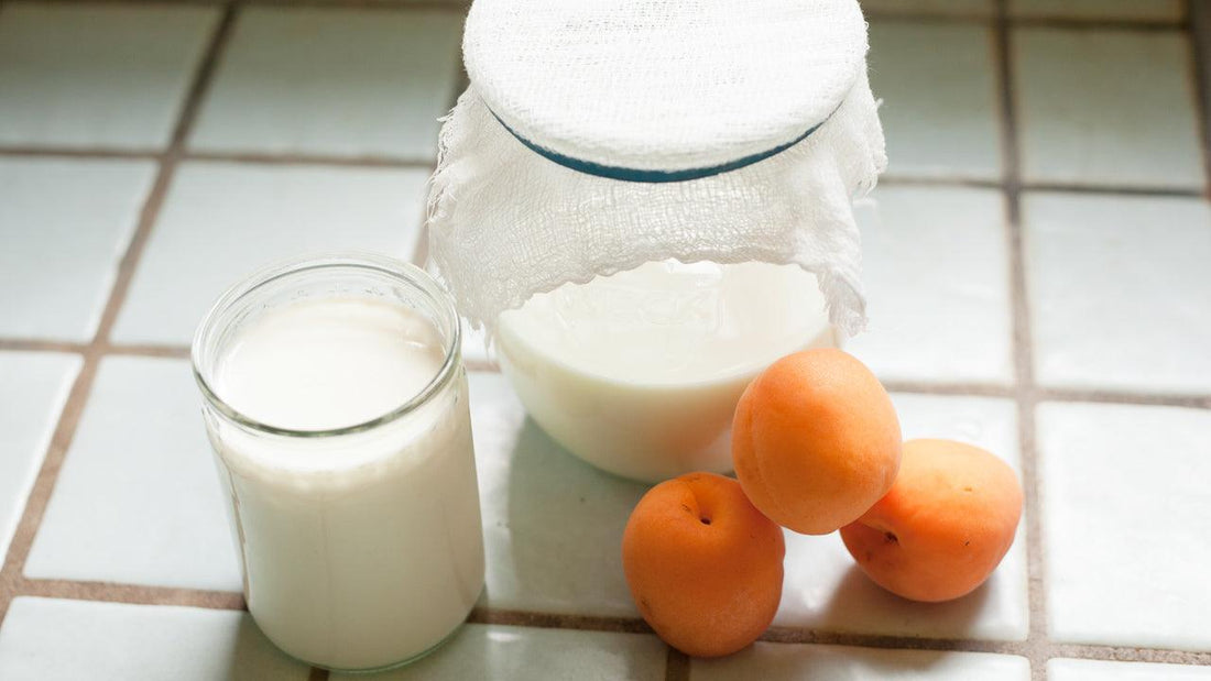 Glass of milk beside a pitcher and oranges