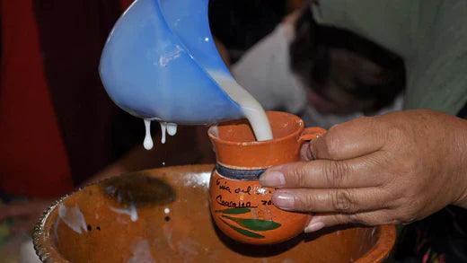Hand pouring liquid into a mug of Mexican atole