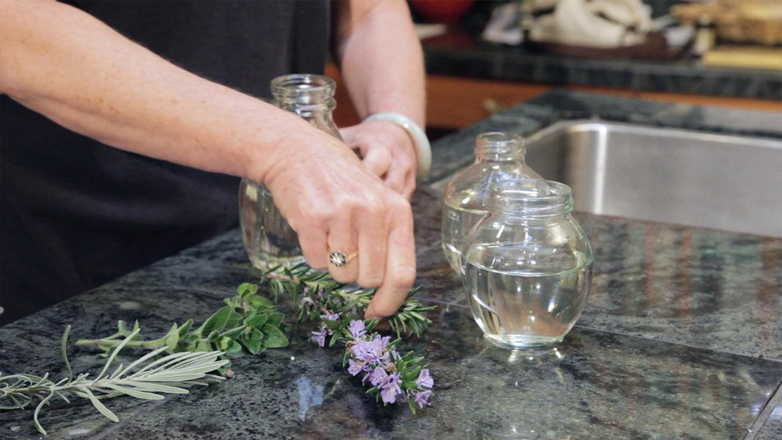 Hands placing herb cuttings into jars of water