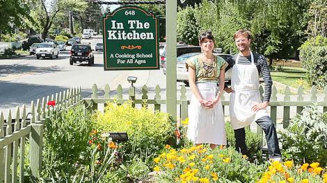 Two women beside a kitchen garden and fermentation sign