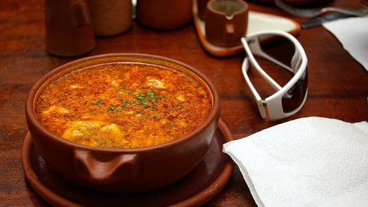 Bowl of garlic soup beside garlic cloves