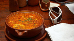 Bowl of garlic soup beside garlic cloves