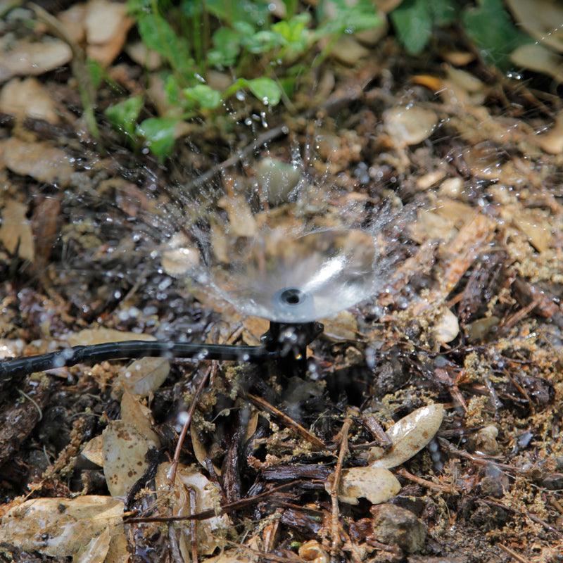 Water flowing from drip irrigation onto mulch in a summer garden