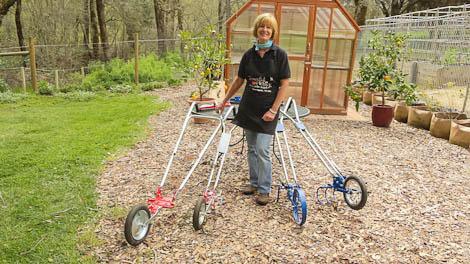 Woman standing with three wheel hoes on a garden path