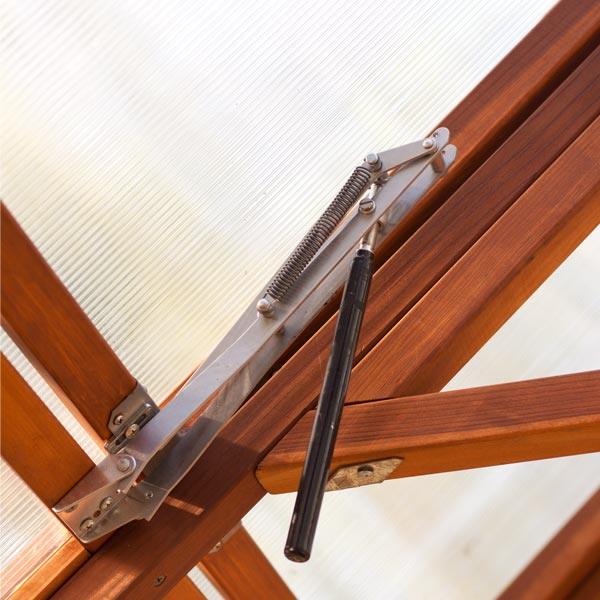 Metal greenhouse vent opener mounted on a roof frame