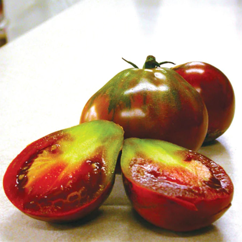 Three Japanese Trifele Black tomatoes, one halved and displayed, All of them displaying varying colors, Turning from green to red 