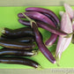 A cutting board full of assorted Asian Trio Eggplants, colors include Deep purple to black, Pink, and a pink shade of white 