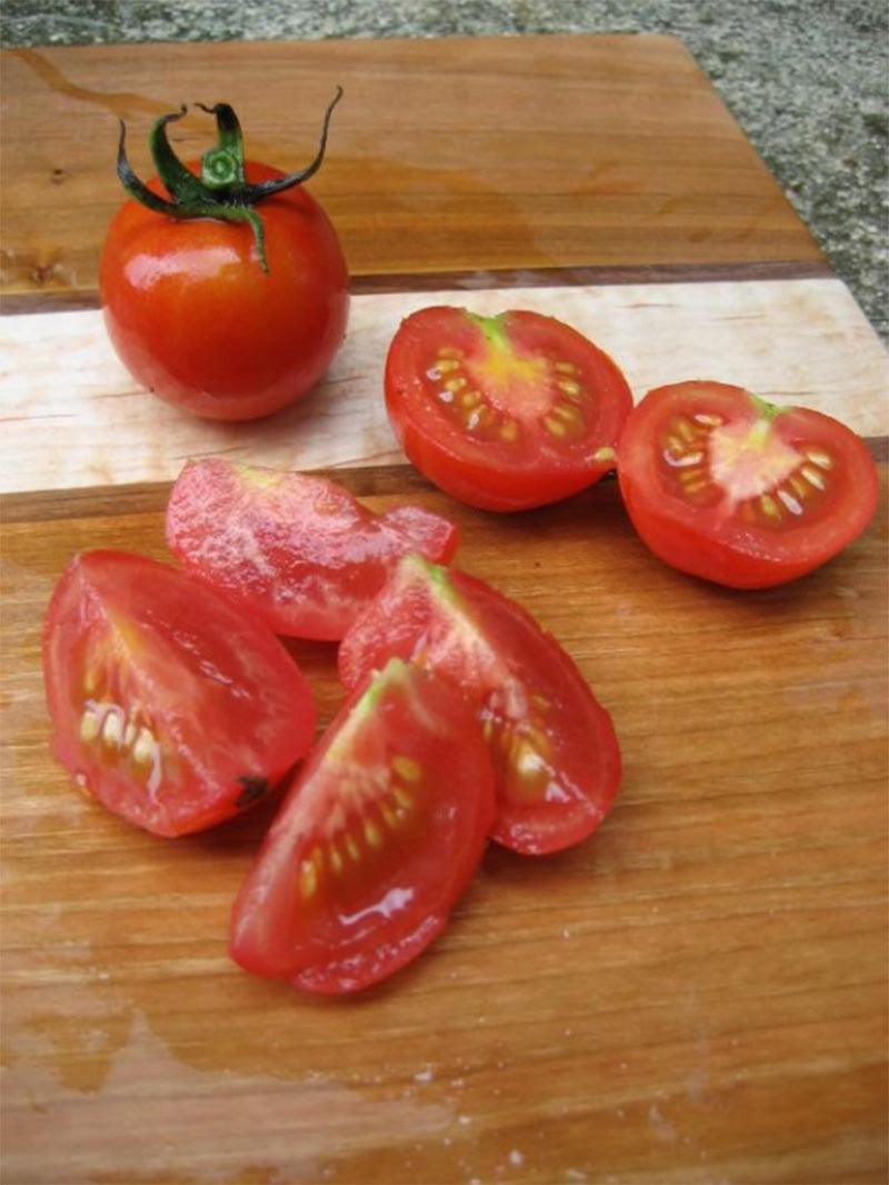 Halved and Quartered Fox Cherry Tomatoes resting on wooden cutting board